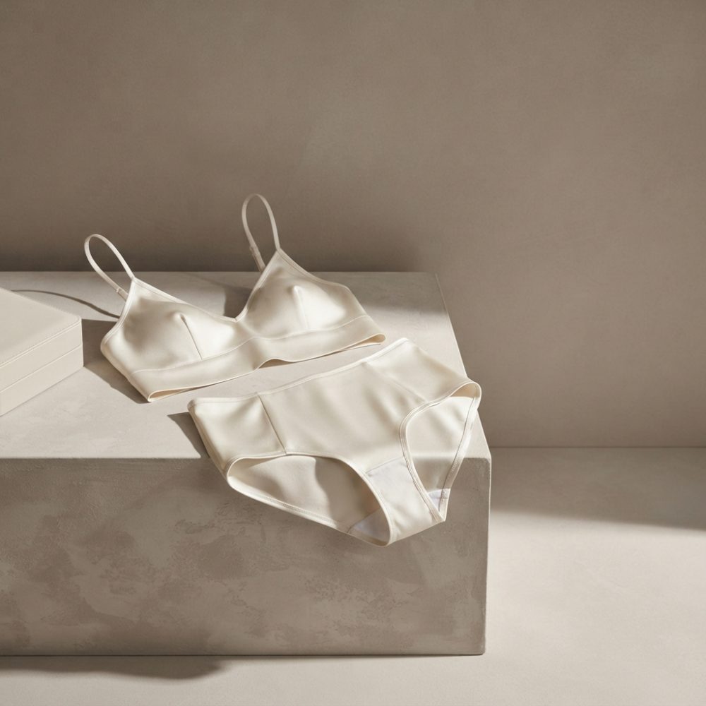 Conjunto de lingerie bege com sutiã de alças finas e cueca de cintura alta sobre superfície neutra