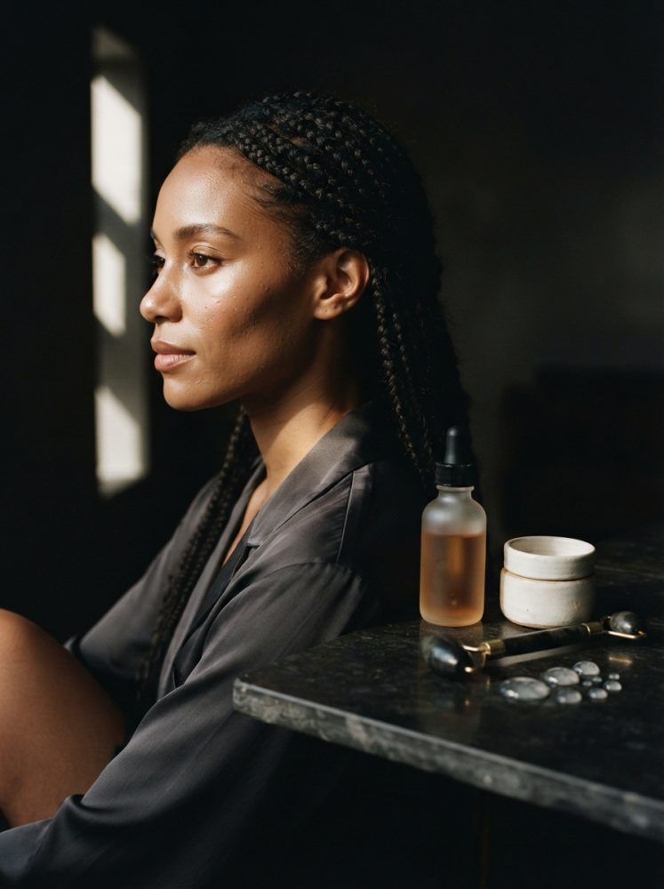 Mulher morena com cabelo trançado sentada perto de produtos de cuidado de pele naturais