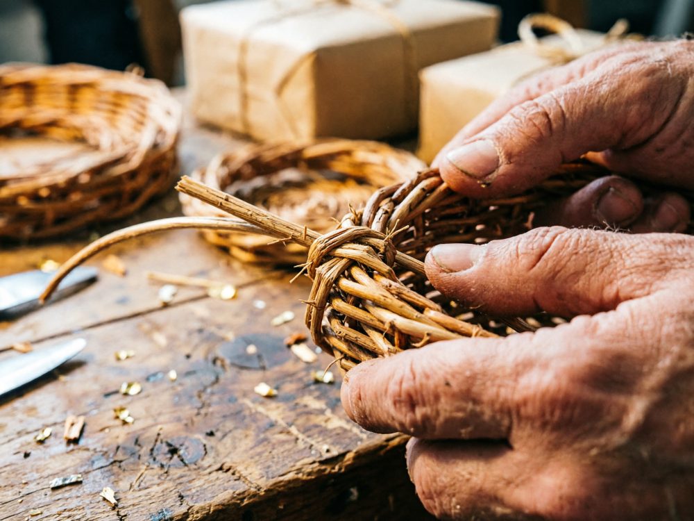 Mãos artesanais trançando cesto de vime numa bancada de madeira rústica