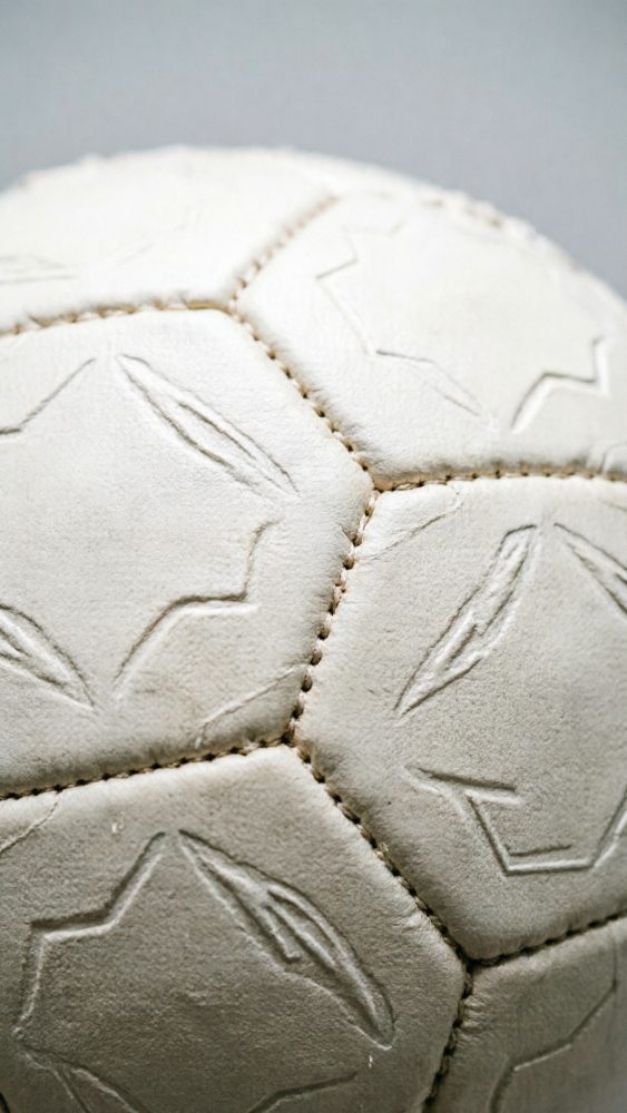 Close-up de bola de futebol branca com textura gravada e costuras visíveis