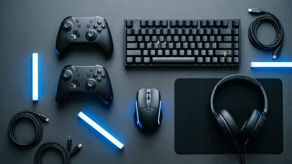Conjunto de acessórios gaming preto com teclado, comandos, rato, auscultadores, cabos e luzes LED azul