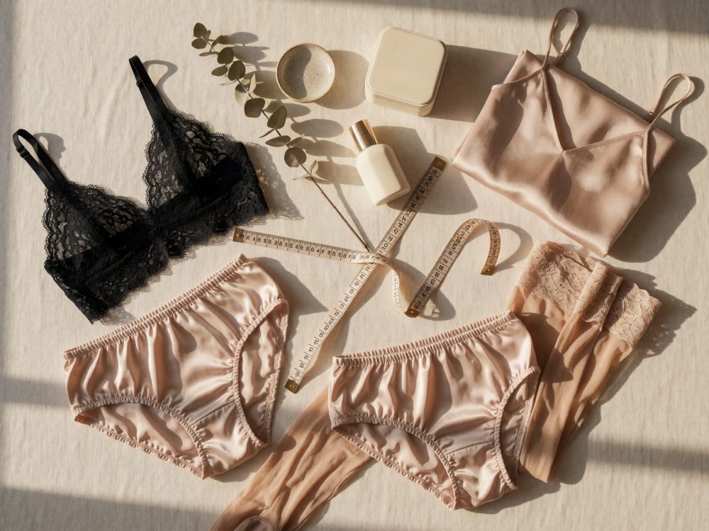 Conjunto de lingerie com soutien de renda preta, cuecas de seda rosa claro e acessórios de beleza