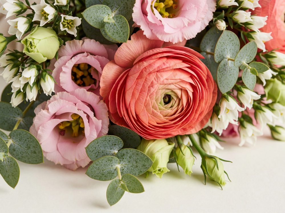 Bouquet com ranúnculo coral, lisianthus rosa, pequenas flores brancas e folhas de eucalipto