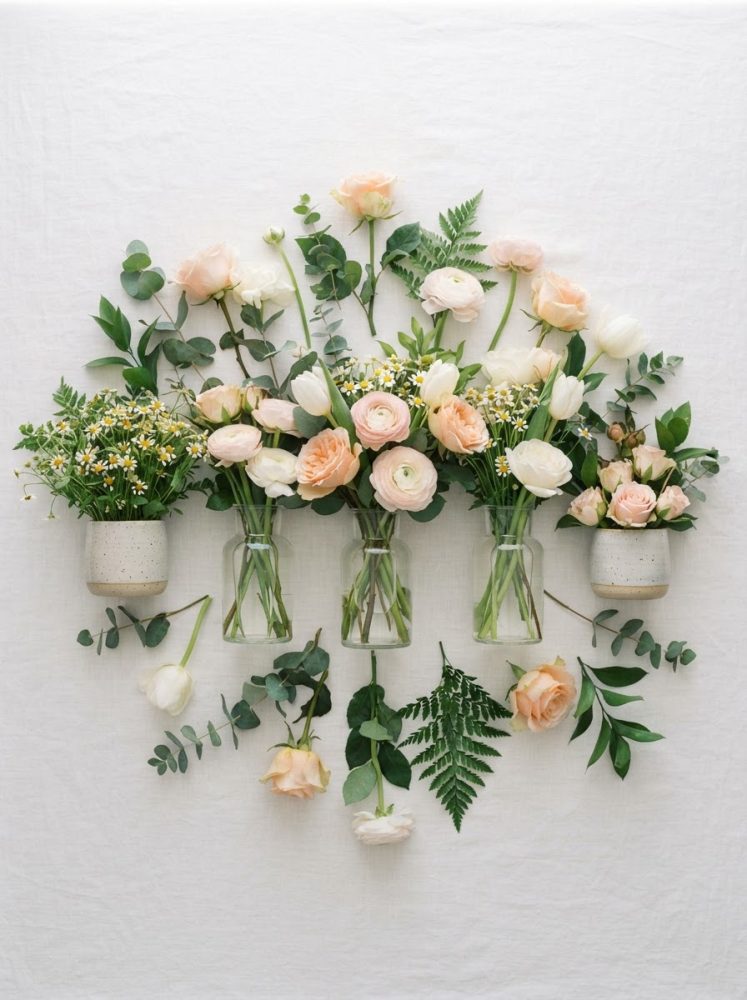 Arranjos florais com rosas, tulipas, margaridas e folhagens em vasos de vidro e cerâmica sobre fundo branco