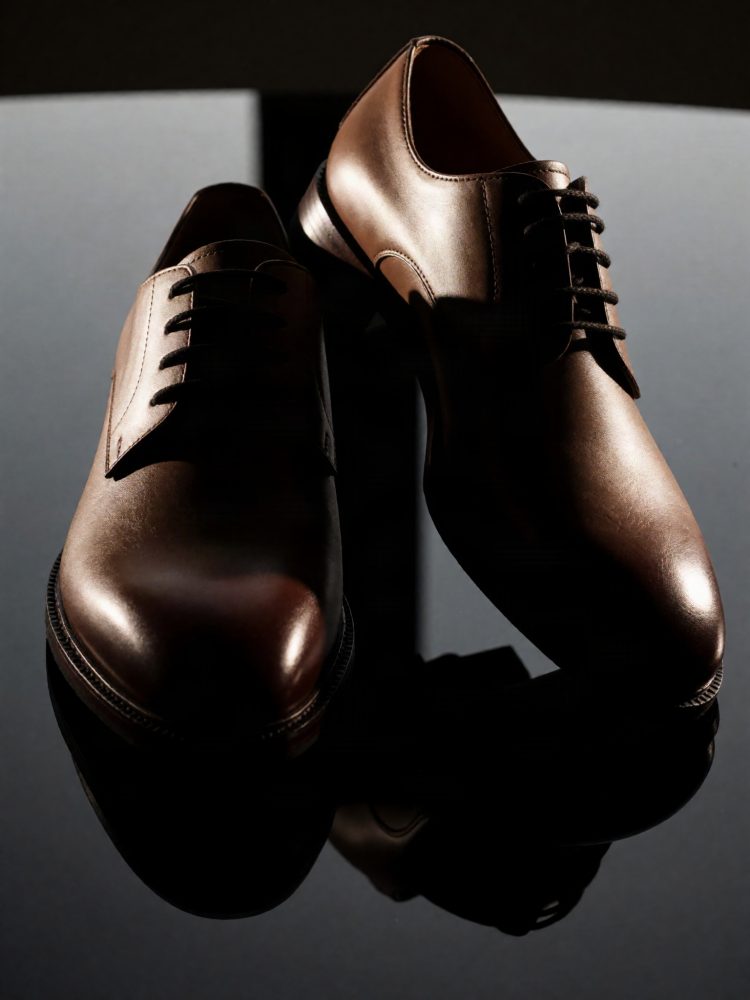 Par de sapatos formais de couro castanho com atacadores pretos sobre fundo escuro