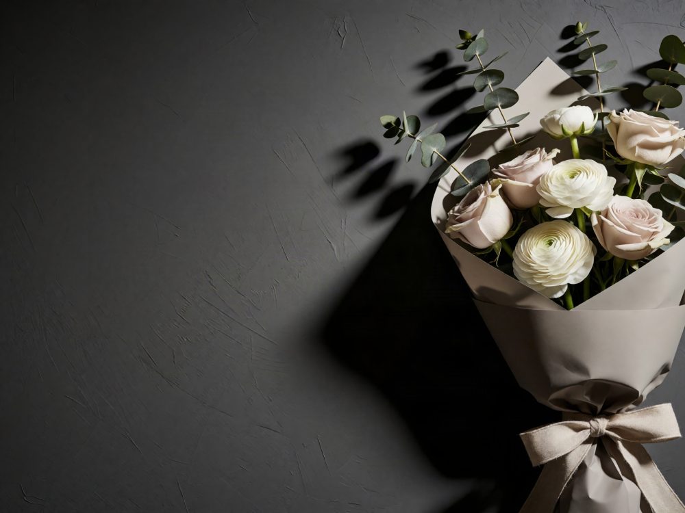 Bouquet de rosas rosas, ranúnculos brancos e eucalipto envolto em papel cinza com laço