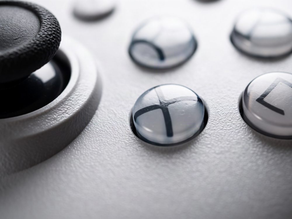 Close-up de botões transparentes com símbolos e joystick preto de comando de videojogos cinzento
