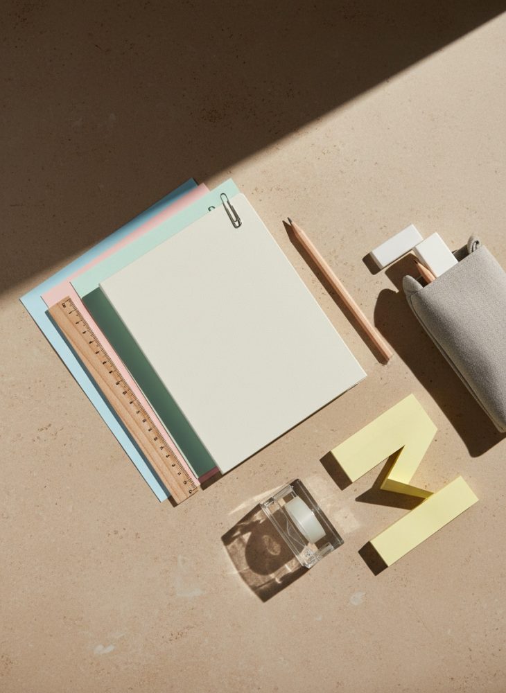 Materiais de papelaria minimalistas sobre superfície clara com luz e sombra