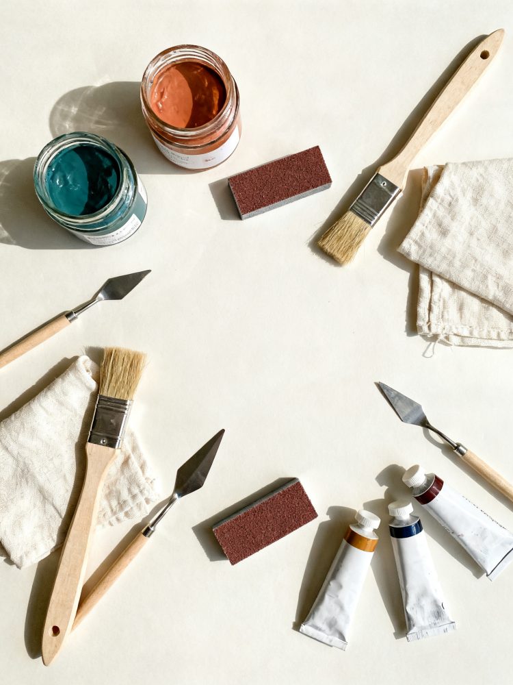 Materiais de restauração: pincéis, tintas, espátulas, lixas e panos sobre fundo claro