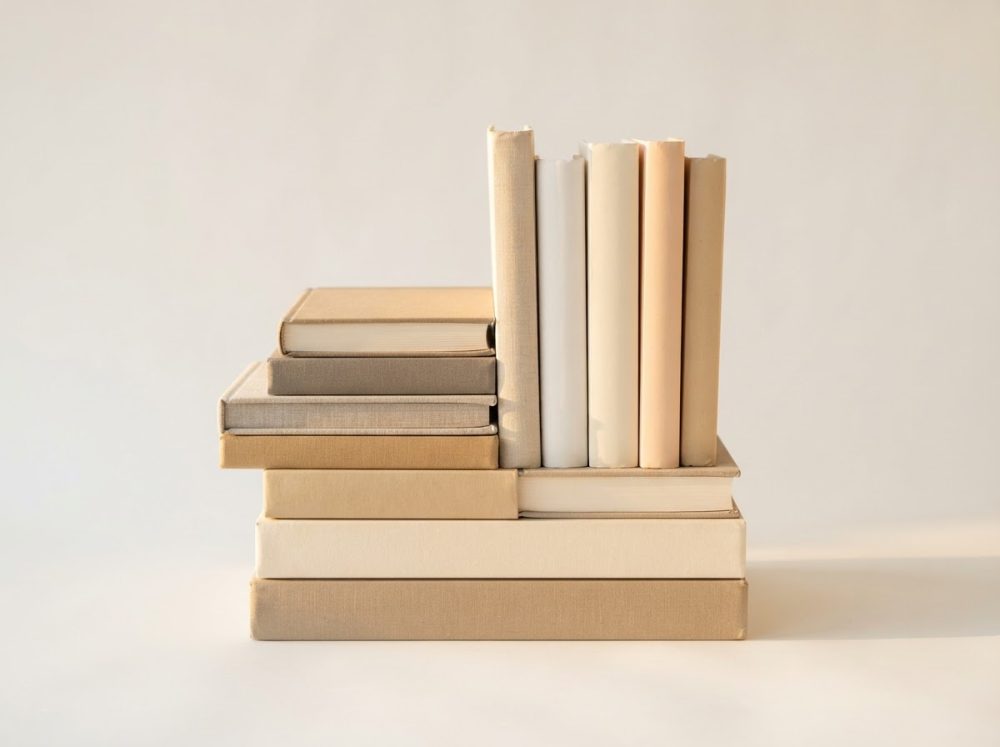Livros empilhados e alinhados em tons neutros sobre fundo claro minimalista