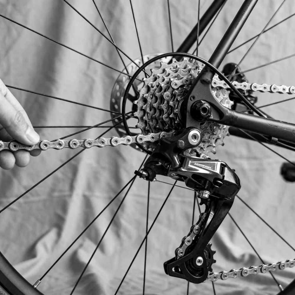 Close-up da corrente e mudanças traseiras de bicicleta com mão a ajustar corrente