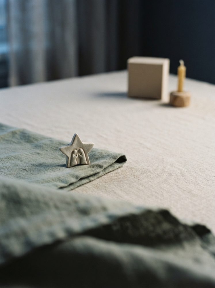 Estrela decorativa natalícia em cerâmica sobre tecido verde numa mesa clara