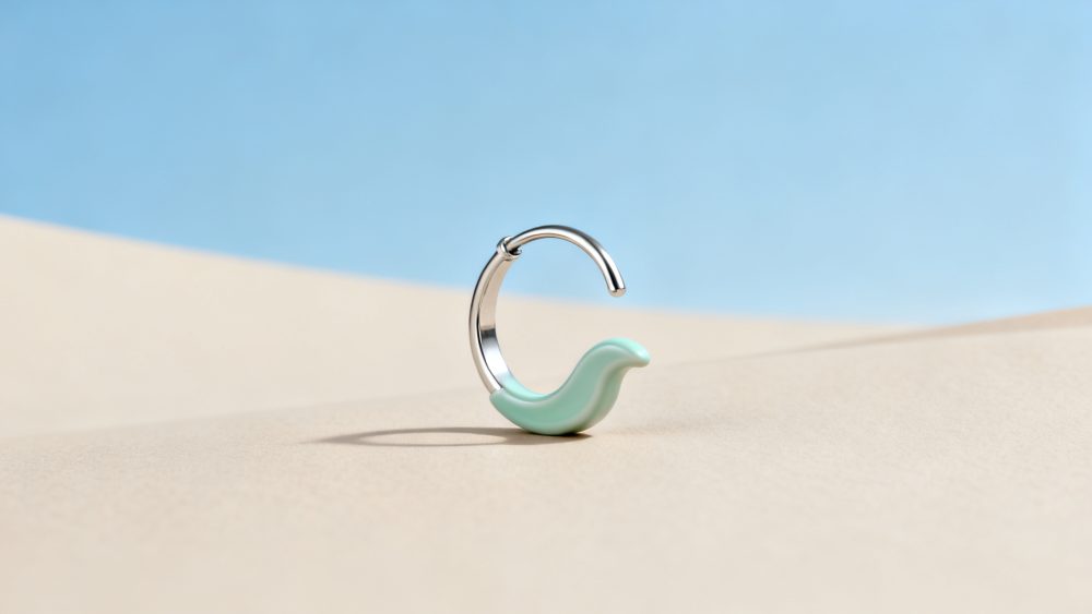 Brinco de argola prateada com detalhe ondulado azul claro sobre fundo bege e céu azul