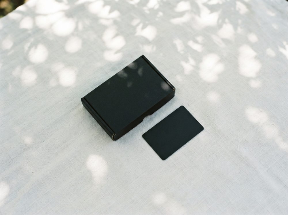 Cartão preto com caixa preta em fundo de tecido com sombras naturais