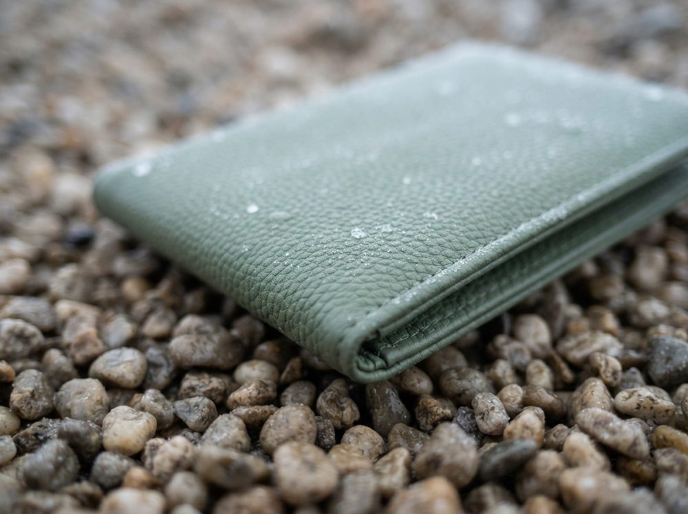 Carteira verde com gotas de água sobre pedras pequenas