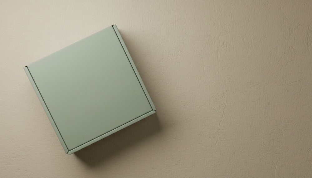 Caixa de embalagem verde sobre superfície bege texturada com luz suave