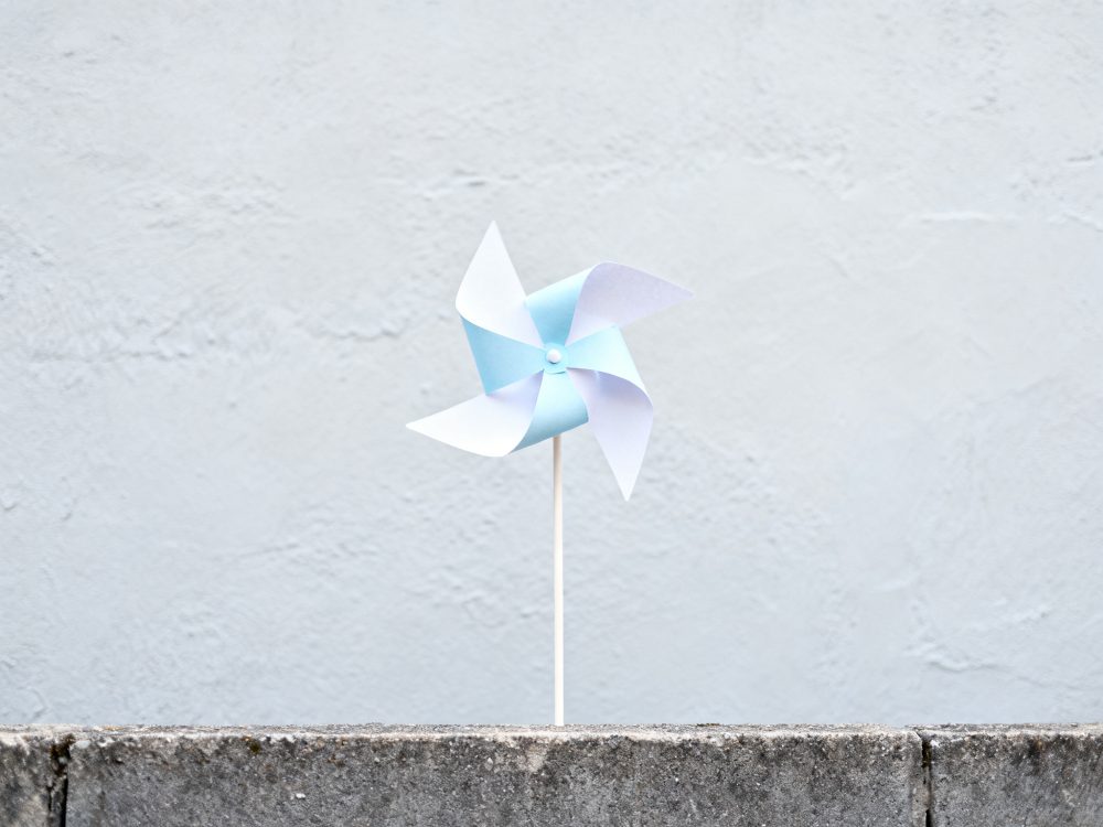 Catavento azul e branco sobre superfície cinzenta de parede texturada