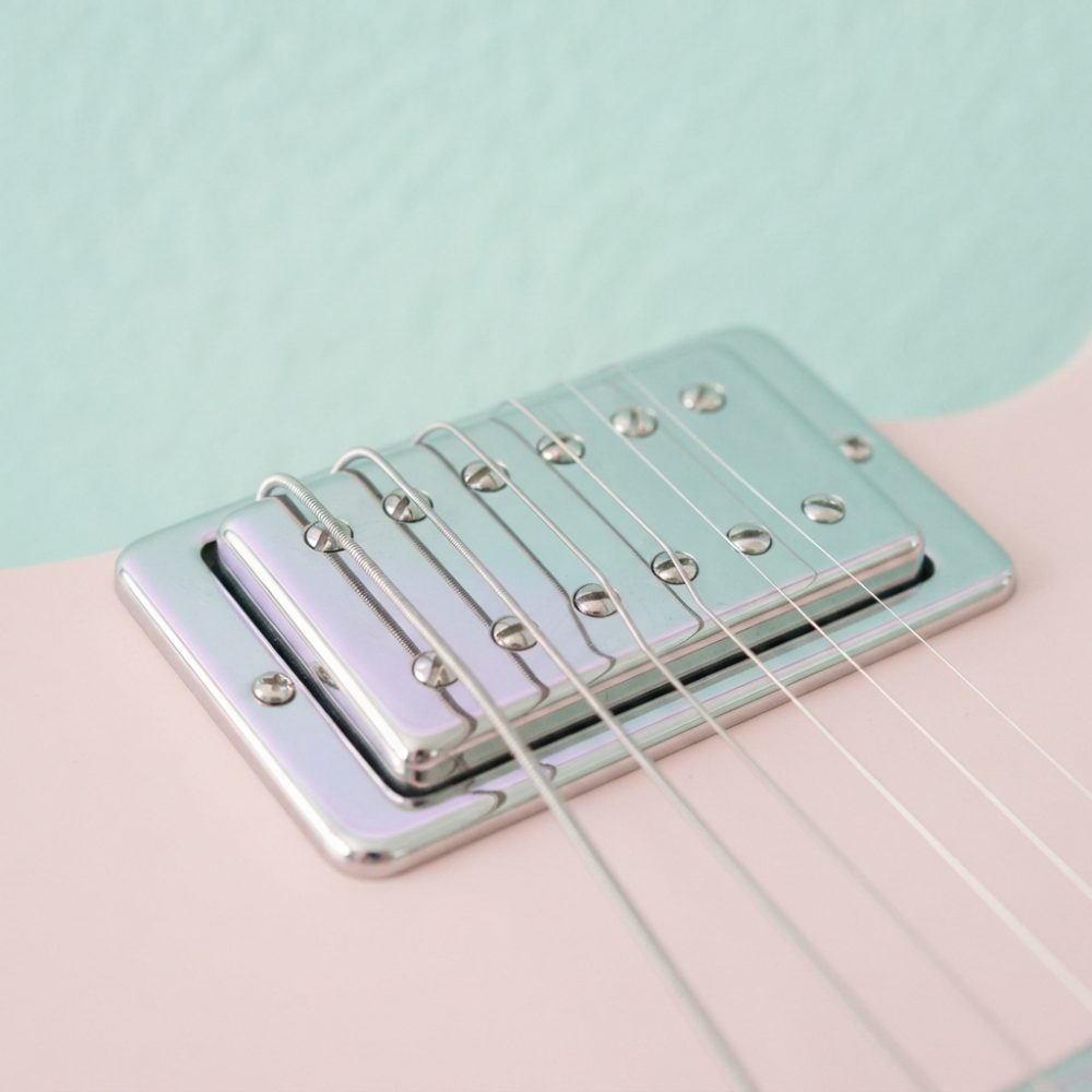Close em ponte e captadores metálicos de guitarra elétrica rosa com cordas visíveis