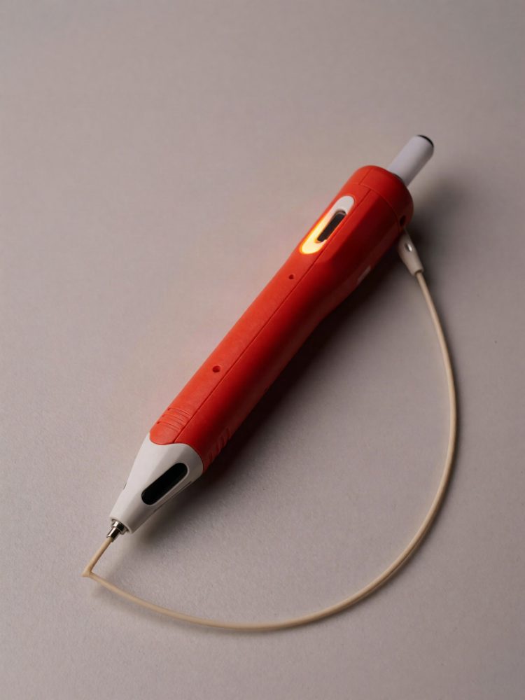 Caneta eletrónica vermelha com cabo USB ligada sobre superfície cinzenta