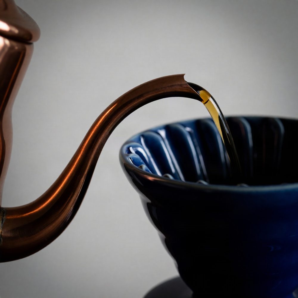 Cafeteira de cobre a verter café num filtro cerâmico azul escuro