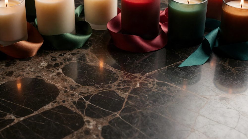 Velas acesas coloridas com fitas de cetim sobre superfície de pedra escura polida