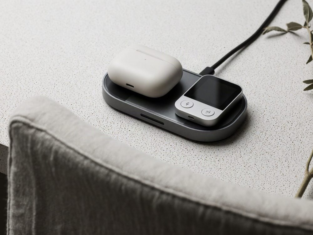 Base de carregamento sem fios com auriculares brancos e leitor digital num espaço claro minimalista
