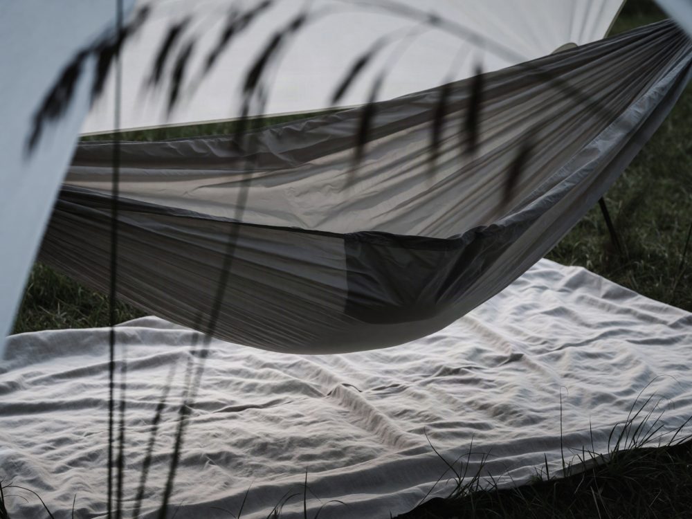Rede cinza suspensa com manta branca em relva verde para campismo