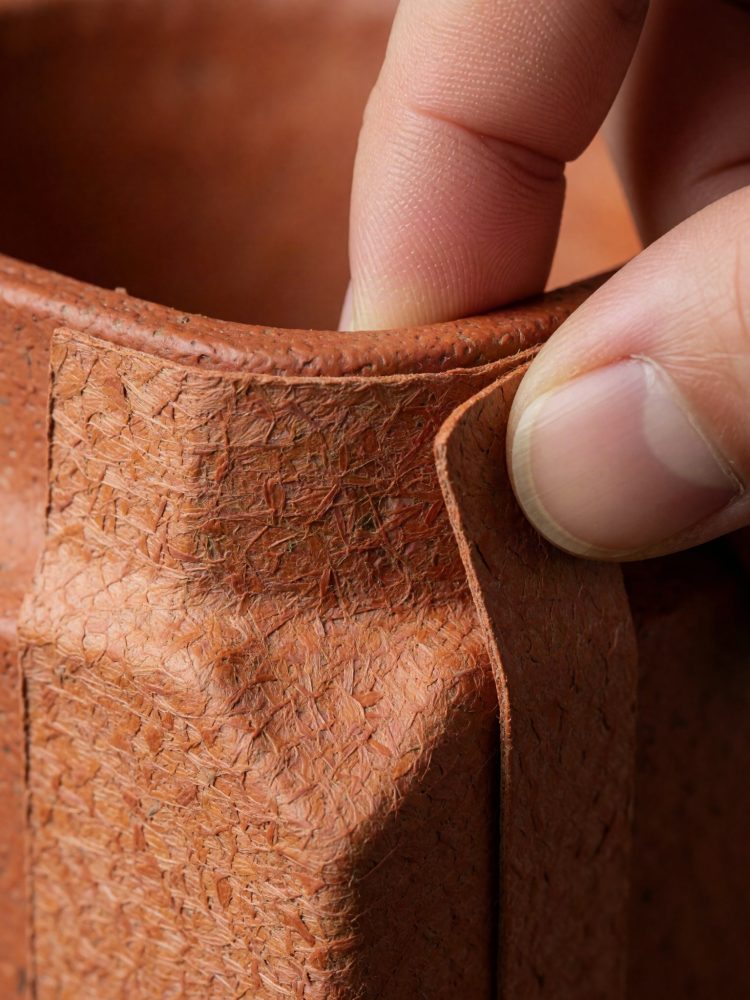 Mão a segurar aba de saco reutilizável castanho com textura rugosa para embalagem