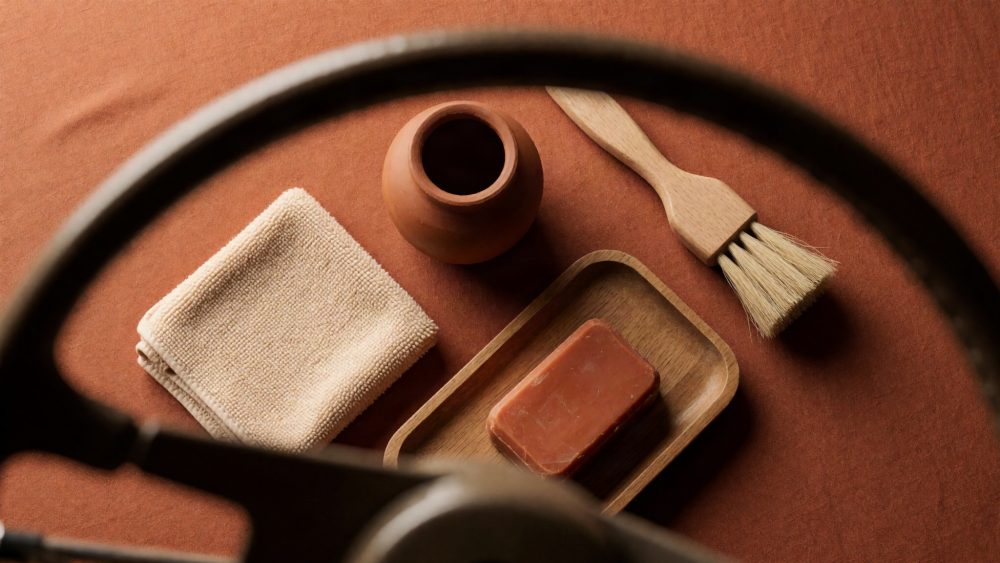 Kit de limpeza para automóveis com pano, pincel, sabonete e frasco de barro em fundo terracota