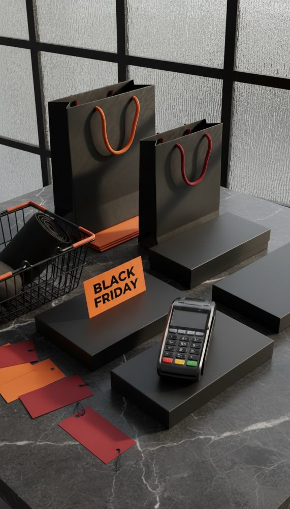 Caixas negras, sacos de compras com cordões laranja e vermelho, etiquetas e cartão Black Friday sobre mesa escura.