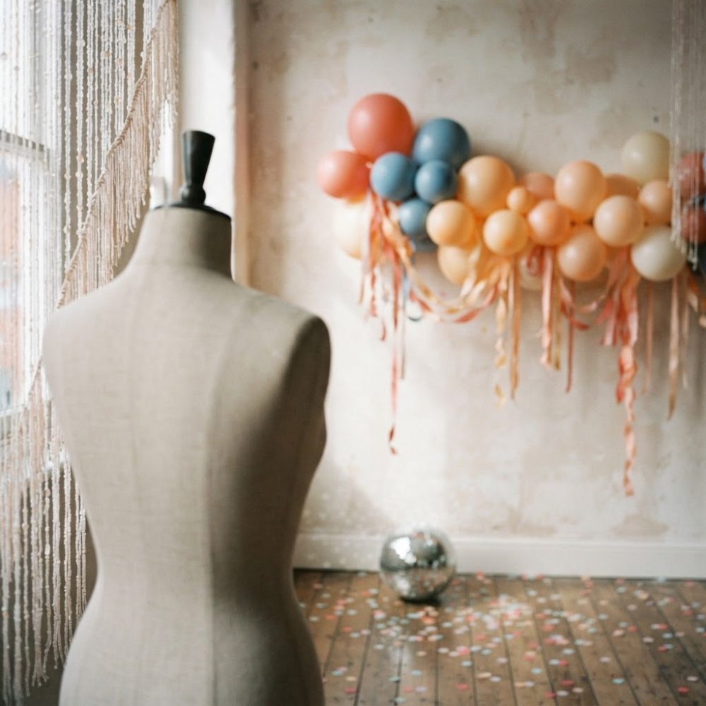 Manequim vintage com balões pastel e esfera espelhada em ambiente decorado para festa
