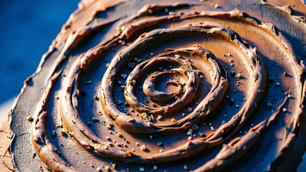 Espiral abstrata em tons castanhos com fundo azul e textura granulada