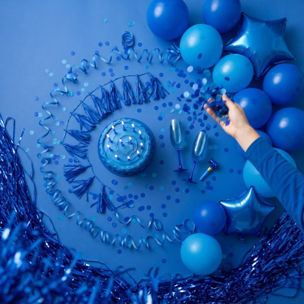 Decoração de festa azul com bolo, balões, serpentinas e confetes