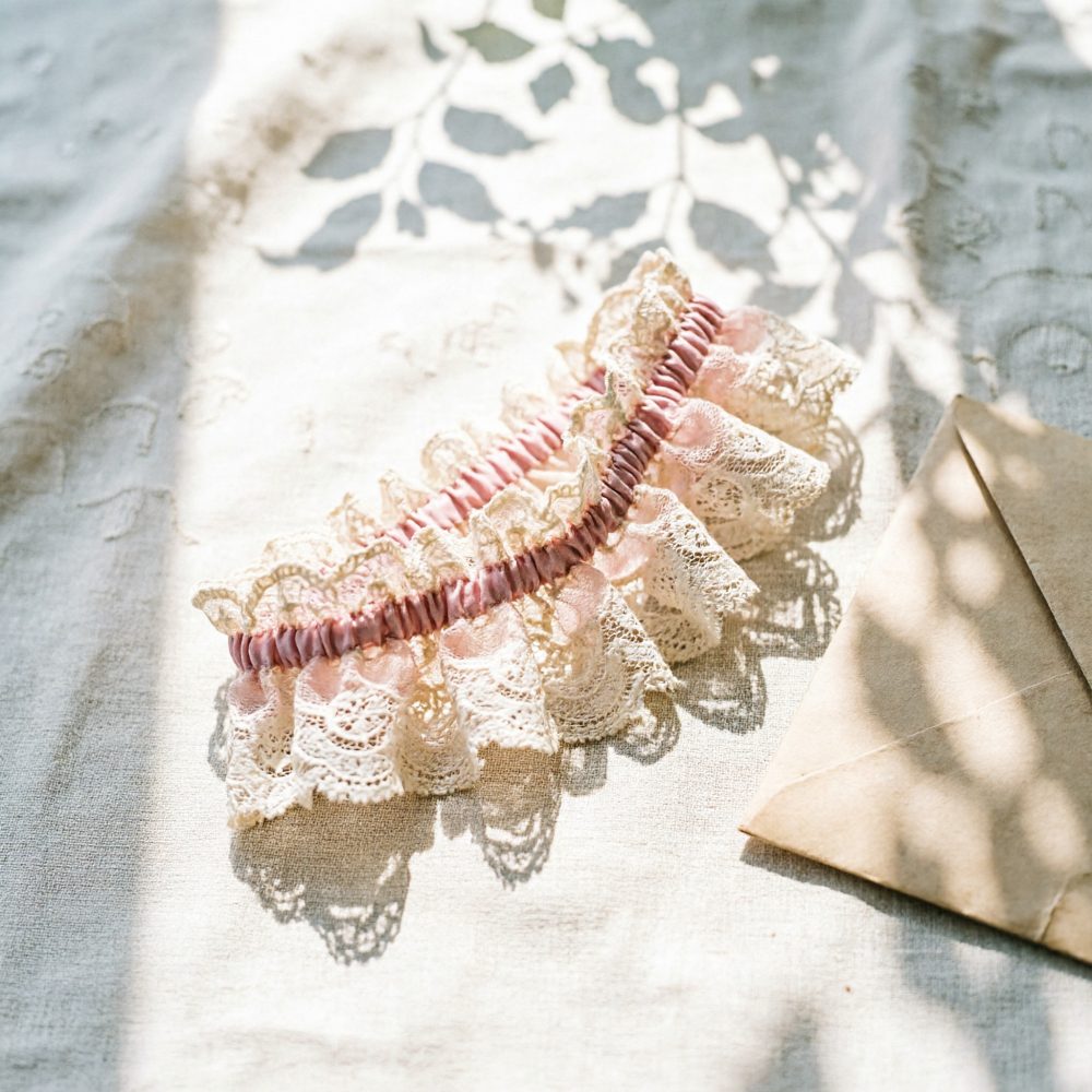 Liga para casamento em renda bege com elástico rosa sobre tecido claro com envelope