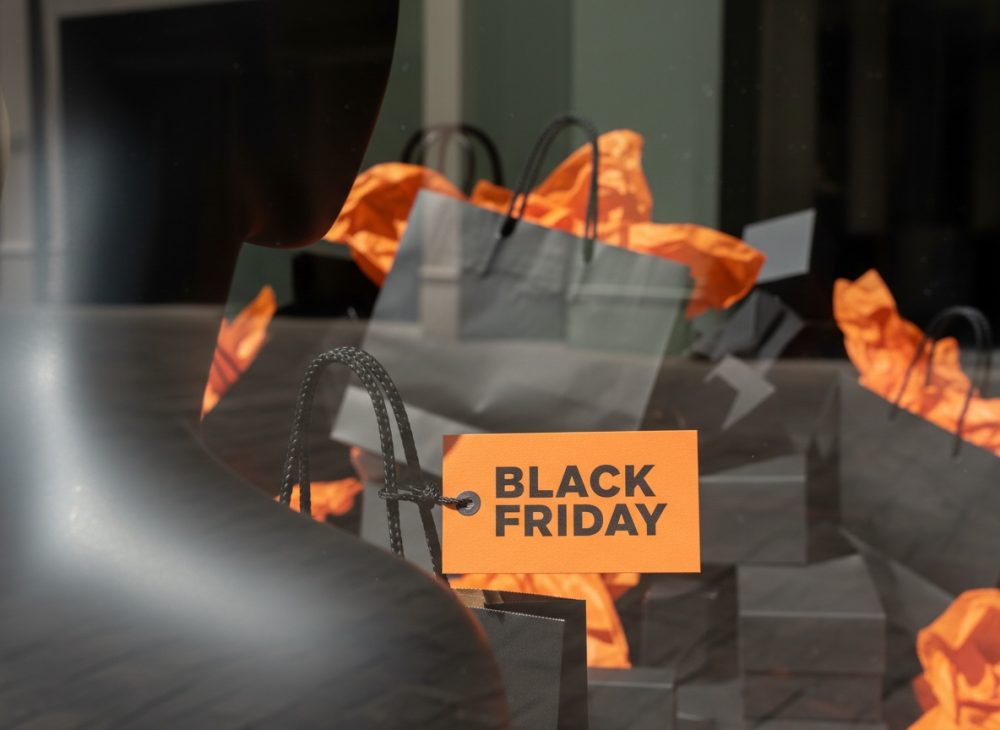 Sacos pretos com papel laranja e etiqueta Black Friday em montra de loja