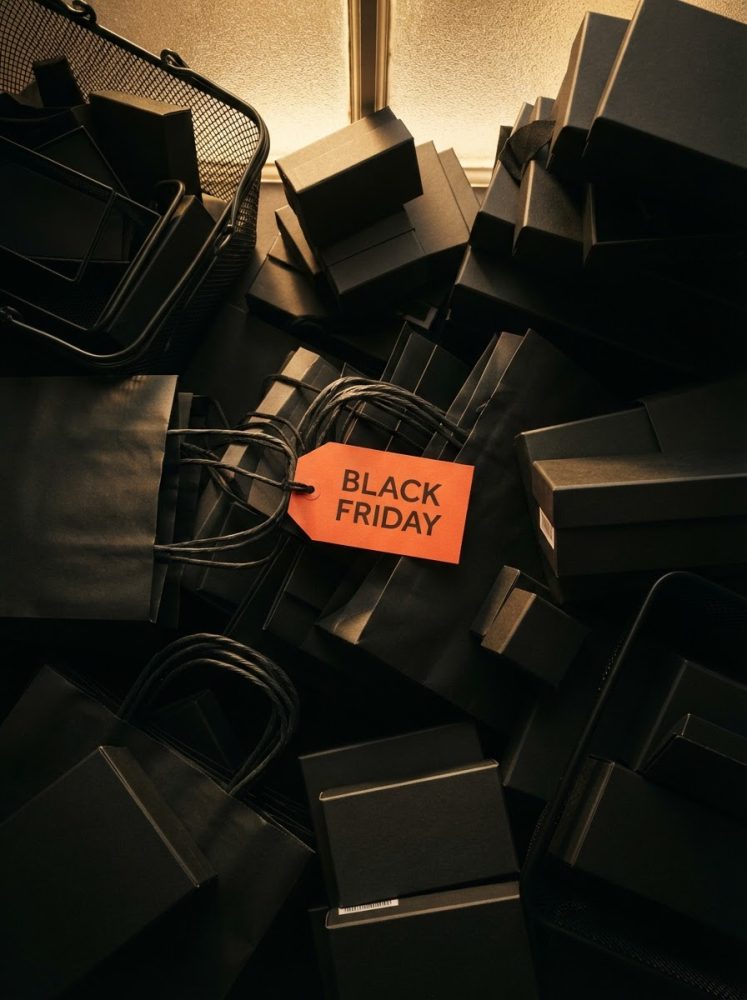 Sacos e caixas pretas com etiqueta laranja destacando Black Friday para promoções