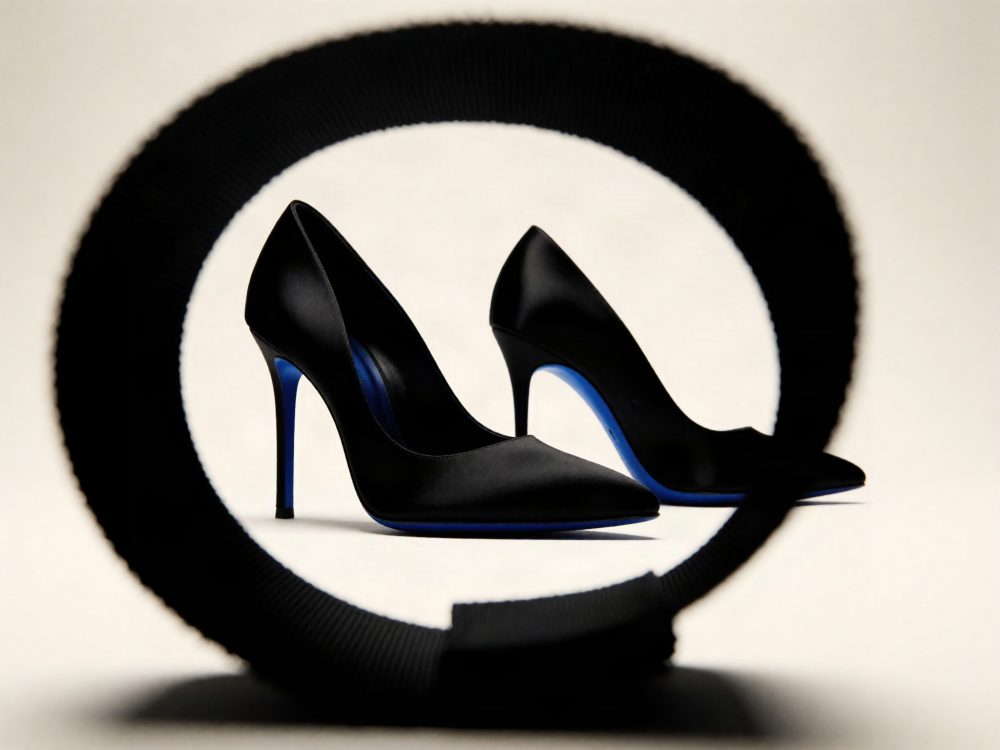 Par de sapatos pretos de salto alto com sola azul em fundo claro com moldura circular preta