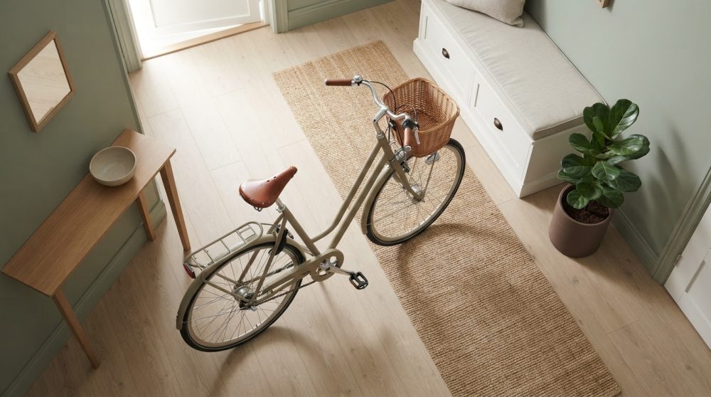 Bicicleta clássica bege com banco castanho num corredor interior com tapete e planta
