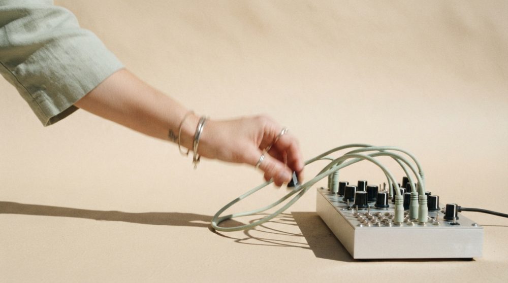 Mesa de mistura modular com cabos e mão ajustando conector sobre fundo bege