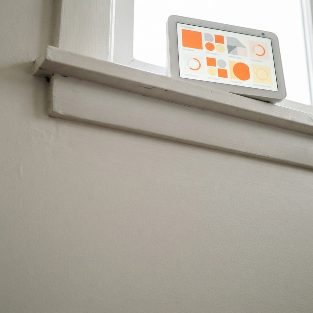 Tablet branco numa soleira de janela com gráficos coloridos no ecrã