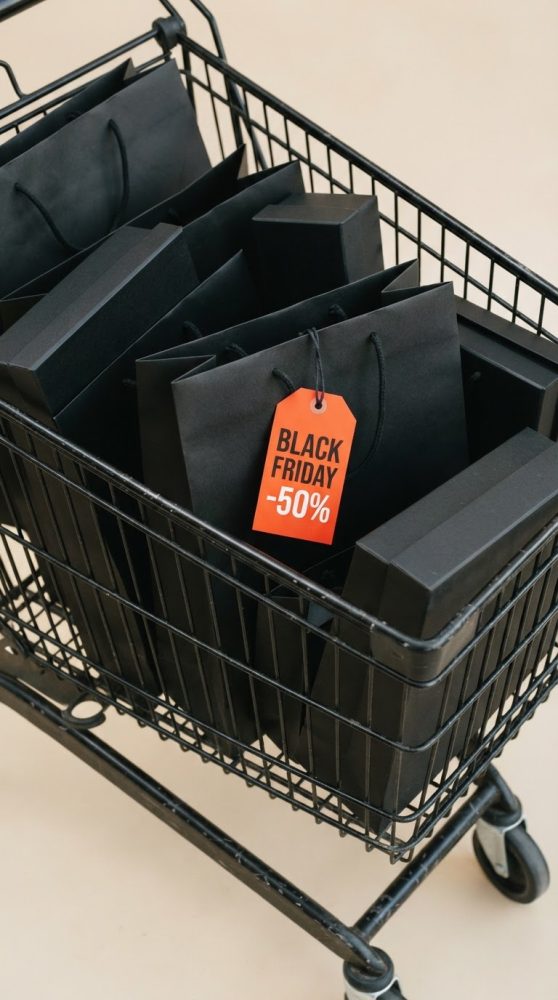 Carrinho de compras preto com sacos pretos e etiqueta vermelha de desconto Black Friday 50%
