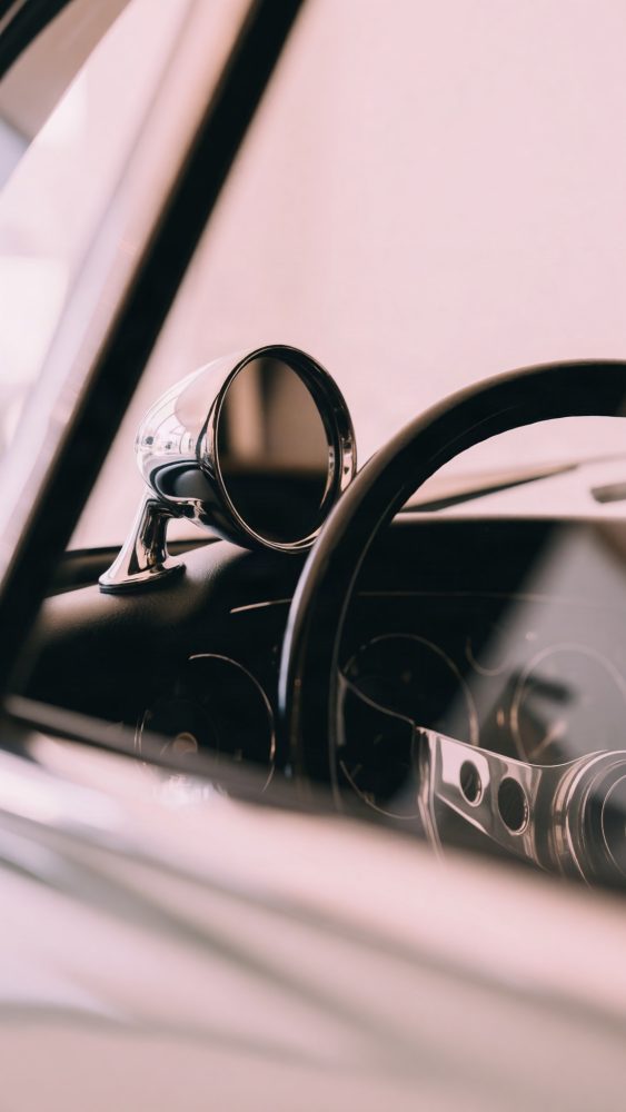 Espelho lateral cromado e volante de automóvel clássico com interior escuro