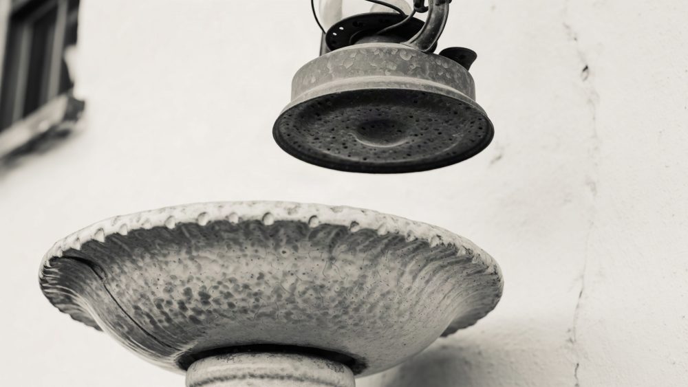 Fonte decorativa metálica com lâmpada vintage suspensa em parede branca