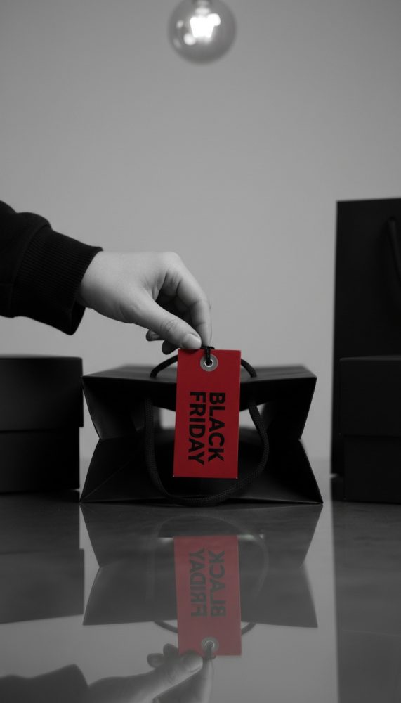 Mão a segurar saco preto com etiqueta vermelha onde está escrito Black Friday