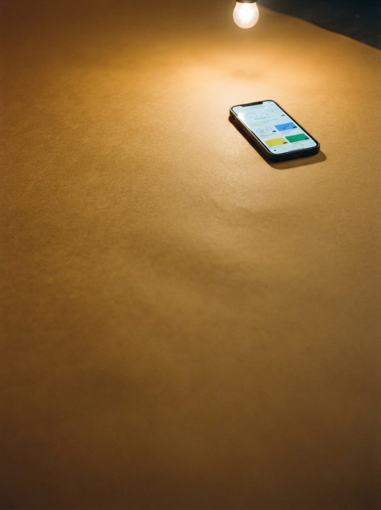 Smartphone com aplicativos abertos iluminado por lâmpada sobre mesa castanha