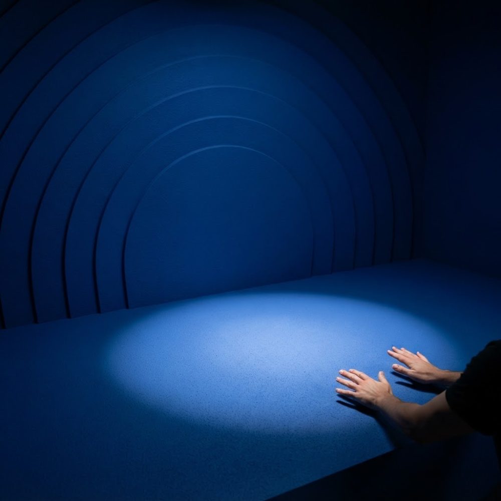 Superfície e fundo azul iluminados com luz circular e mãos tocando superfície
