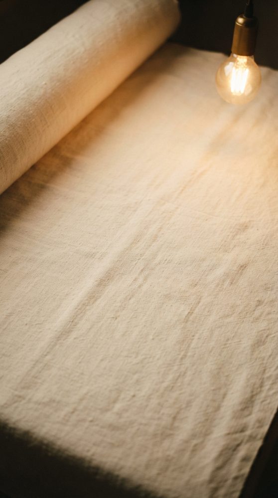 Detalhe de tecido bege desenrolado com luz quente de lâmpada ao lado