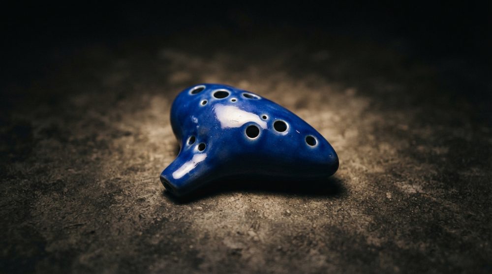 Instrumento musical ocarina cerâmica azul sobre fundo escuro