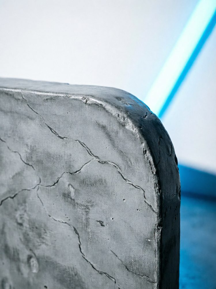 Superfície próxima de cimento com textura e rachaduras iluminada por luz azul suave
