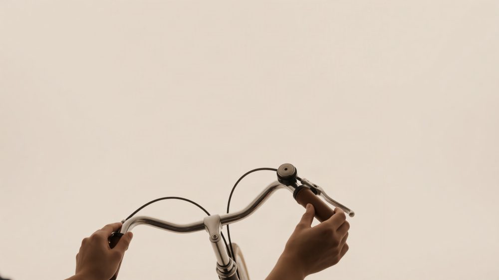 Guiador de bicicleta clássico com mãos segurando num fundo bege neutro